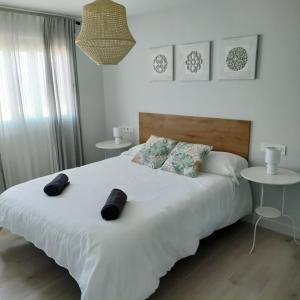 a bedroom with a large white bed with two tables at Villa Memé Playa in Málaga