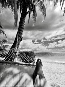 アロランギにあるRarotonga Villas Absolute Beachfrontの浜辺のハンモックに横たわる者