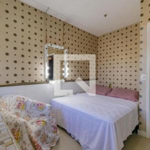 Apartamento Top Barra da Tijuca في ريو دي جانيرو: غرفة نوم بسرير ومرآة وكرسي