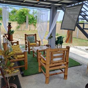 patio con sedie e tavolo su un tappeto verde di The Beaulah Overlooking Cozy Hideaway in Hundred Islands a Alaminos
