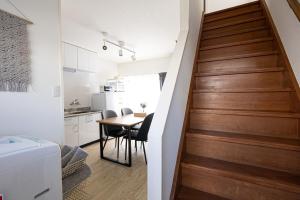 a staircase leading up to a kitchen and a dining room table at Lino下伊福 in Okayama