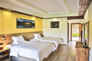 2 camas en una habitación con paredes amarillas en 九寨沟阿布氇孜民宿Jiuzhaigou Valley Abluzi B&B, en Jiuzhaigou