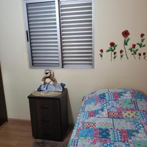 Meu Cantinho في كامبيناس: سرير مع دمية الدب يجلس على خزانة في غرفة النوم