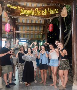 un grupo de personas posando para una foto bajo una señal en Phong Nha Cherish House en Phong Nha