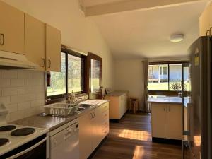 Aircabin｜KANGY ANGY｜Lovely｜4 Beds Holiday House في Tuggerah: مطبخ مع الأجهزة البيضاء والأرضيات والنوافذ الخشبية