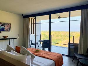 ein Hotelzimmer mit einem Bett und einem großen Fenster in der Unterkunft MAUA Nusa Penida Bali in Nusa Penida