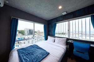 een slaapkamer met een bed en een groot raam bij Hotel CABANA カバナ 宮古島 in Miyako Island