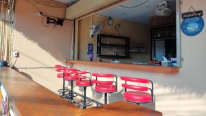a row of red stools at a bar at Lucky Buako Hotel Patong in Patong Beach