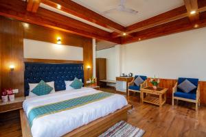 - une chambre avec un grand lit et deux chaises bleues dans l'établissement FabHotel La Kailasha Regency, à Manali