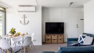 a living room with a blue couch and a tv at On the Beach in Fingal Bay