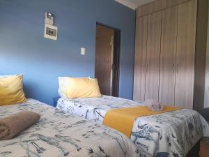 Duas camas num quarto com paredes azuis em The Rose Guesthouse em Witbank