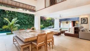 an open living room with a large wooden table and chairs at Casa Mateo Villa in Seminyak