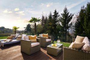 a patio with wicker chairs and couches on a deck at SalvatoreHomes - Luxury Villa with private Dream Garden & BBQ - Casa Palma - a 5 Star Luxury Collection at Lake Garda in San Zeno di Montagna