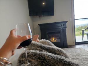 a person holding a glass of wine in front of a fireplace at The Top Place Retreat in Caveside