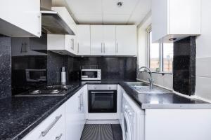 a kitchen with white cabinets and black counter tops at Dagenham Self Catering 4BedHouse sleeps up to 8 with Free Wifi and Free Parking in Dagenham
