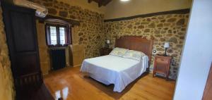 um quarto com uma cama num quarto com paredes de pedra em Fuente de Güelo em San Bartolomé de Meruelo