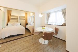 ein Hotelzimmer mit 2 Betten, einem Tisch und Stühlen in der Unterkunft CITY HOTEL Namba Residence 2 in Osaka