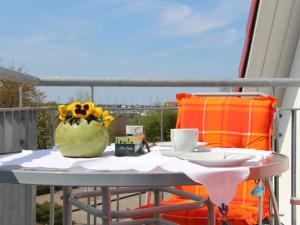 a table with a vase of flowers and a cup on a balcony at Chudzik Modern retreat in Rerik