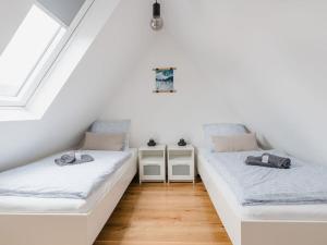 two beds in a room with white walls and wooden floors at Torbogenhuus No 5 in Norderney