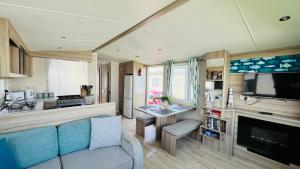 a living room with a couch and a kitchen at Luxurious caravan in Lyons Holiday Park Rhyl in Meliden