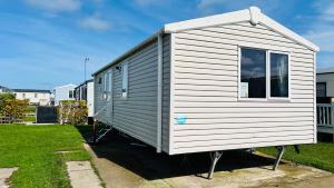 a white tiny house sitting in a yard at Luxurious caravan in Lyons Holiday Park Rhyl in Meliden