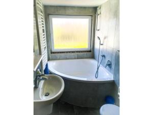 een badkamer met een bad, een wastafel en een raam bij Borkum Freedom 2 in Borkum