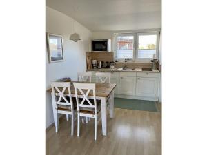 eine weiße Küche mit einem Holztisch und Stühlen in der Unterkunft Holiday home Fischer in Juist