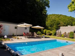 a swimming pool with two umbrellas next to a house at Palatinate Forest Comfortable holiday residence in Silz
