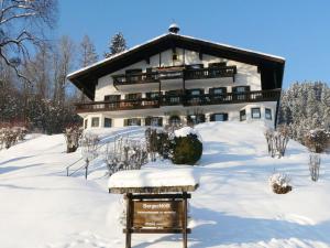 ein großes Gebäude im Schnee mit einem Schild davor in der Unterkunft 7 Bergschlössl Modern retreat in Oberaudorf