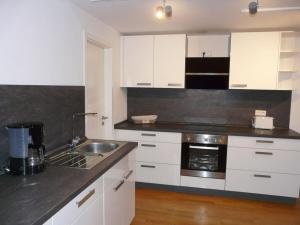 a kitchen with white cabinets and a sink at Kampenwand Loft Modern retreat in Aschau