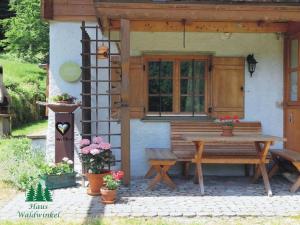 a wooden table and bench in front of a house at Nagelsmederij in het huis Waldwinkel in Aschau im Chiemgau