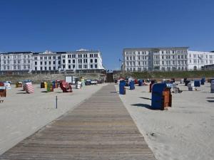 a beach with a wooden boardwalk in front of buildings at Siam Comfortable Holiday Residence in Borkum