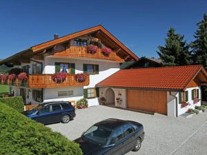 a house with two cars parked in a parking lot at Holiday apartment Zugspitze in Krün