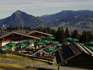 un restaurant avec des parasols verts, des tables et des montagnes dans l'établissement Bader Modern retreat, à Blaichach