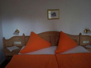 uma cama com duas almofadas laranjas em cima em Bader Modern retreat em Blaichach