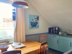 a kitchen with a wooden table and a blue boat on the wall at Colorful Cow Modern Retreat in Borkum