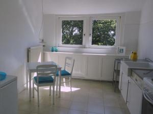 een keuken met een tafel en stoelen en 2 ramen bij The large holiday apartment in WÃ¶lpinghausen
