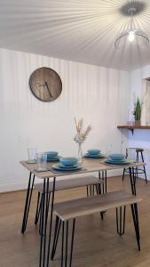 a dining room table with a clock on the wall at City Centre Apartment by Noire Property in Manchester