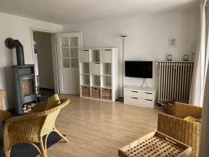 ein Wohnzimmer mit einem TV, einem Sofa und Stühlen in der Unterkunft Holiday apartment at Molopark in Murnau am Staffelsee