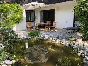 un patio con un estanque con una mesa y una sombrilla en Holiday apartment at Molopark, en Murnau am Staffelsee