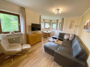 uma sala de estar com um sofá de couro e uma televisão em Holiday apartment No 5 Bergschlössl em Oberaudorf