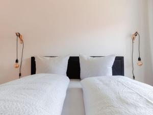 2 camas con sábanas blancas y luces en la pared en Granetal Quartier-Apartment Wildblume en Goslar