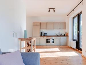 cocina con armarios blancos y sofá azul en Granetal Quartier-Apartment Wildblume en Goslar