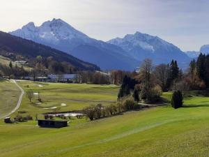 uitzicht op een golfbaan met bergen op de achtergrond bij Hirschbichler Modern retreat in Berchtesgaden