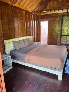 Łóżko w drewnianym pokoju z drewnianą podłogą w obiekcie Telagamas Guest House w mieście Banjarangkan