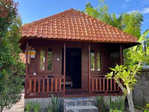 drewniany dom z werandą i dachem w obiekcie Telagamas Guest House w mieście Banjarangkan