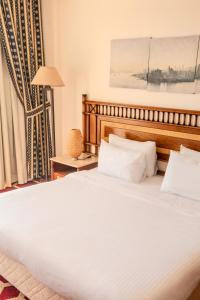 a bedroom with a large white bed with a wooden headboard at Om Kolthom Hotel in Cairo