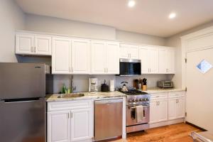 a kitchen with white cabinets and stainless steel appliances at Sunny,cozy,near Bc,bu,boston,mbta in Boston