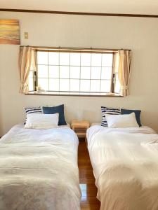 zwei Betten in einem Zimmer mit Fenster in der Unterkunft 一棟貸し別荘つる in Matsue