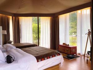 1 dormitorio con 2 camas y ventana grande en 九寨沟阿布氇孜民宿Jiuzhaigou Valley Abluzi B&B, en Jiuzhaigou